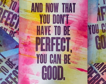 May include: A rectangular card featuring a watercolor background with blended yellow, orange, and pink hues. The text in dark purple reads: AND NOW THAT YOU DON'T HAVE TO BE PERFECT, YOU CAN BE GOOD. The card is surrounded by similar prints.