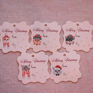 May include: Five decorative gift tags with a scalloped edge. Each tag features a watercolor illustration of a cat or dog wearing a holiday hat and scarf. The text "Meowy Christmas" and "Merry Christmas" are printed on the tags, with space to write "From:" and "To:"