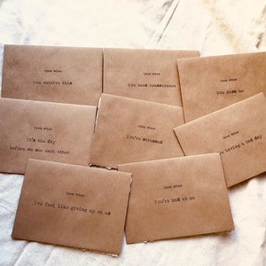May include: A set of ten brown paper envelopes with handwritten messages on each. The messages include "Open when you receive this", "Open when you're stressed", "Open when you're having a bad day", "Open when you miss me", "Open when you feel like giving up on us", "Open when you're mad at me", "Open when it's the day before we see each other", and "Open when you need reassurance".