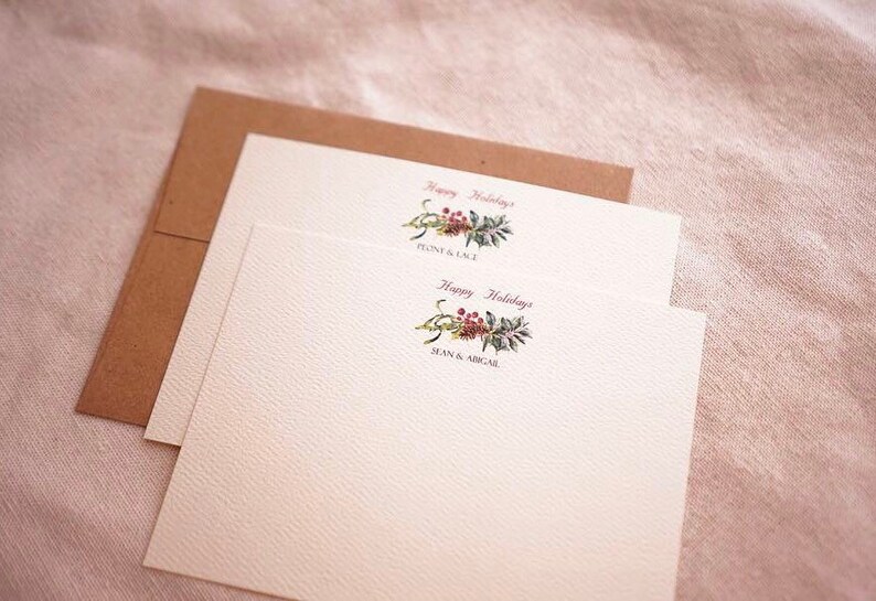 May include: Two white cards with a green and red floral design and the text "Happy Holidays" with the names "Flynn & Lacy" and "Sean & Abigail" printed below.
