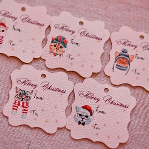 May include: Five decorative gift tags with scalloped edges. Each tag features a watercolor illustration of a cat wearing a winter hat and scarf. The tags read "Meowy Christmas" with space for "From:" and "To:"