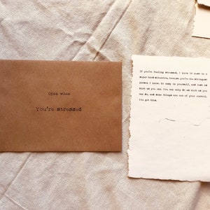 May include: A brown paper envelope with the words "Open when you're stressed" printed on the front. The envelope contains a handwritten note that reads: "If you're feeling stressed, I know it must be a super hard situation, because you're the strongest person I know. Go easy on yourself, and just do as much as you can. You can only do as much as you can do, and some things are out of your control. You got this."