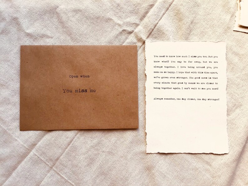 May include: A brown envelope with the text "Open when you miss me" printed on it. A handwritten note inside the envelope reads "You need to know how much I miss you too. But you know what? You may be far away, but we are always together. I love being around you, you make me so happy. I hope that with this time apart, we've grown even stronger. The good news is that every minute that goes by means we are closer to being together again. I can't wait to see you next! Always remember, one day closer, one day stronger!"