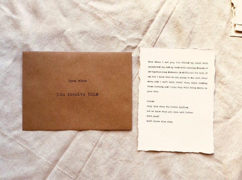 May include: A brown envelope with the text "Open when you receive this" printed on it. Next to the envelope is a piece of paper with the text "Ever since I met you, you filled my heart with unexpected joy and my head with amazing dreams of us together. Long distance is difficult for both of us, but I know that we are going to see each other soon, and I can't wait until then. Enjoy reading these letters, and I hope they will bring a smile on your face.  Salam. Only open when the letter applies. Let me know when you open each letter. Don't peek! Don't throw them away."