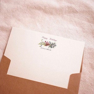 May include: A white card with a brown envelope. The card has a floral design with the text "Happy Holidays" and "Sean & Micael" printed on it.