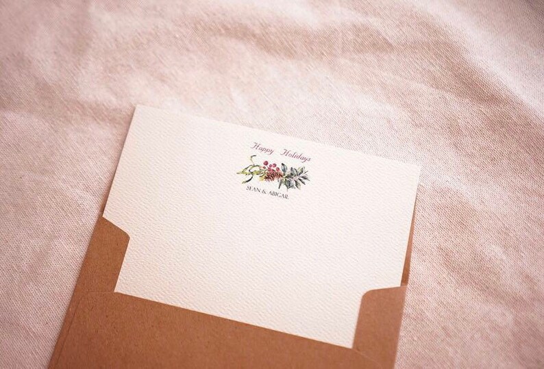 May include: A white card with a brown envelope. The card has a floral design with the text "Happy Holidays" and "Sean & Micael" printed on it.