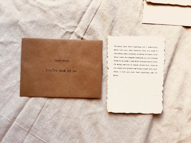 May include: A brown envelope with the text "Open when you're mad at me" on the front. A handwritten note on a piece of paper reads "I'm sorry that we're fighting, but I absolutely will love you. Take whatever time you need to calm down, and I probably am doing the same. Even when I make the biggest mistakes, you are always first in my mind. I just don't always realize what I'm doing and how it makes others feel. This is our chance for growth and being honest with each other. I love you more than anything, and I'm sorry."