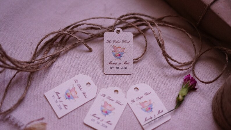 May include: Four cream-colored gift tags with a brown twine string. Each tag has a watercolor illustration of a teacup and saucer with the text "The Perfect Blend" and "Mandy & Matt" with the date "09.30.2018".