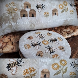 May include: Two beige fabric pillow covers with embroidered bee motifs. The larger pillow has the text "To Bee Free" and the smaller pillow has bees and honeycombs.