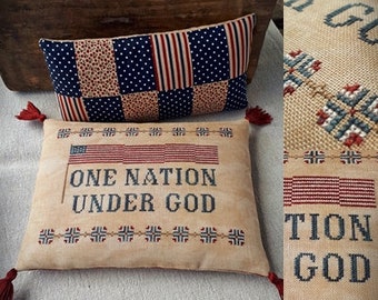 May include: Two decorative cushions with patriotic designs. The top cushion has a patchwork pattern in blue, red, and tan. The bottom cushion displays the text "ONE NATION UNDER GOD" with an American flag. Both cushions have red tassel detailing.