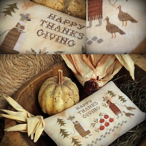 May include: A rectangular fabric cushion featuring cross-stitch embroidery with the text HAPPY THANKSGIVING, depicting a mouse figure, pine trees, turkeys, and red apples. The cushion is placed in a wooden bowl with a small pumpkin and dried corn.