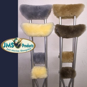 May include: Two crutches with sheepskin covers in gray, tan, and brown. The covers are made of merino sheepskin. The crutches are made of metal. The text "JMS Products Just Merino Sheepskin" is visible in the image.