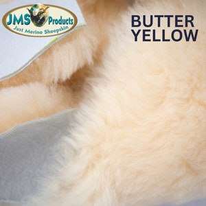 May include: Close-up of a soft, light beige sheepskin rug. The rug is made of natural sheepskin and has a fluffy texture. The text "BUTTER YELLOW" is visible in the upper right corner of the image.