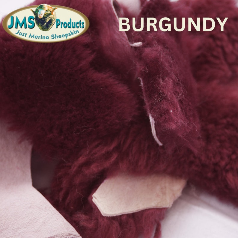 May include: Close-up of a burgundy sheepskin with a white seam. The sheepskin is soft and fluffy. The text "JMS Products Just Merino Sheepskin" is visible in the top left corner. The text "BURGUNDY" is visible in the top right corner.