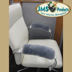 May include: Gray sheepskin armrest covers for an office chair. The covers are made of soft, plush sheepskin and are designed to provide comfort and support. The chair is white leather with a chrome base. The image includes the text "JMS Products Just Merino Sheepskin".