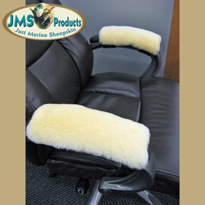 May include: A pair of white sheepskin armrest covers for an office chair. The covers are made of soft, fluffy sheepskin and are designed to provide comfort and support for your arms.  "JMS Products Just Merino Sheepskin" is printed on a brown oval label.