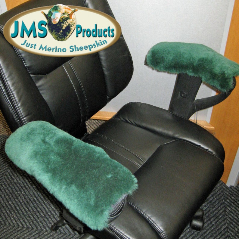 May include: A black office chair with two green sheepskin armrest covers. The chair has a high back and a padded seat. The armrest covers are made of soft, plush sheepskin. The chair is in a room with a light-colored wall and a carpet.