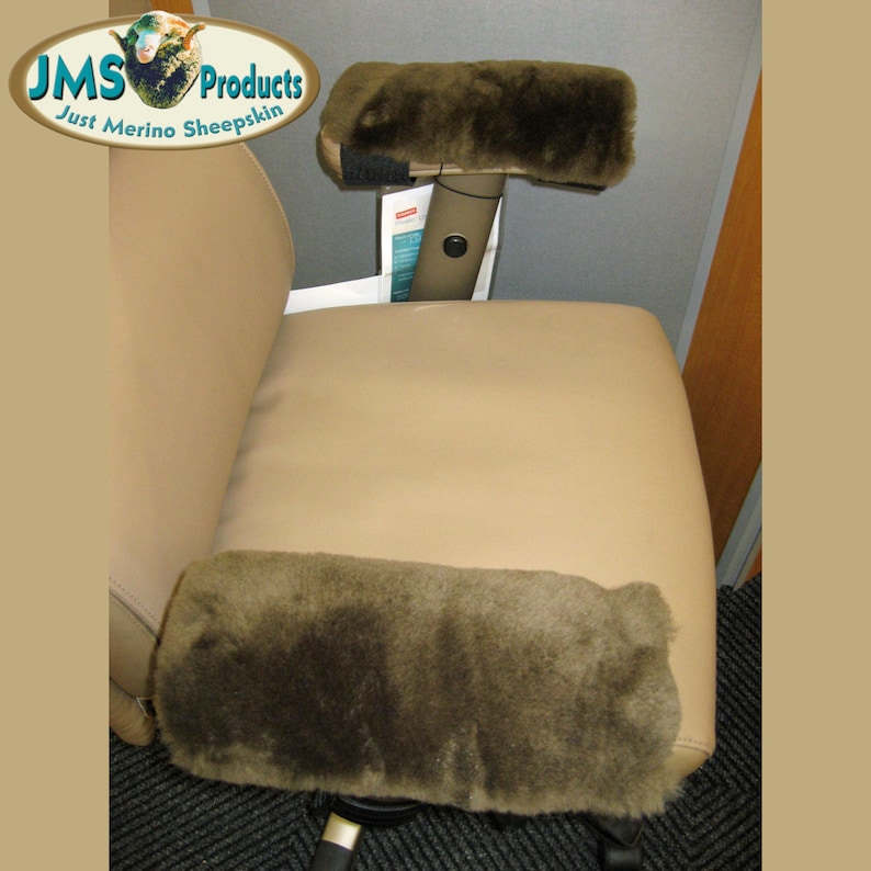 May include: Two brown sheepskin armrest covers for an office chair. The covers are made of soft, plush sheepskin and are designed to provide comfort and support. The covers are attached to the armrests with velcro straps.