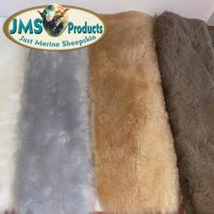 May include: Close-up of three merino sheepskin rugs in white, gray, and tan. The rugs have a soft, fluffy texture. The top left corner of the image features a logo that reads "JMS Products Just Merino Sheepskin."