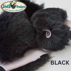 May include: Close-up of black sheepskin fur. The fur is soft and fluffy. The sheepskin is folded over, showing the underside of the material. The text "BLACK" is printed in white letters on a black background.