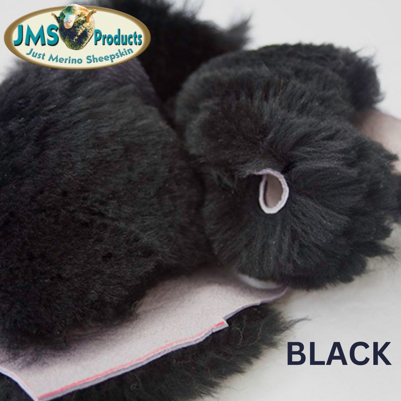 May include: Close-up of black sheepskin fur. The fur is soft and fluffy. The sheepskin is folded over, showing the underside of the material. The text "BLACK" is printed in white letters on a black background.
