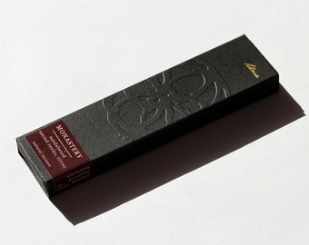 Peut inclure: Boîte noire de bâtonnets d'encens avec inscription dorée "MONASTERY" et "sandalwood, sacred resins, citrus, natural incense".