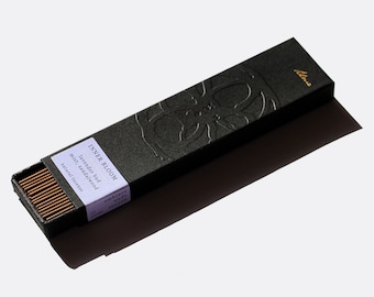 May include: A black box of incense sticks with gold lettering that reads "INNER BLOOM lavender bud mist sandalwood natural incense". The box has a raised design of a flower.