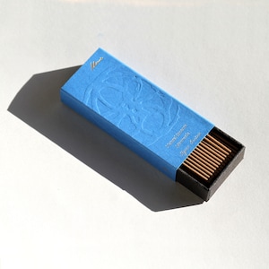 May include: A blue box with a floral design and the word "Mini" printed on the top. The box contains a pack of incense sticks.