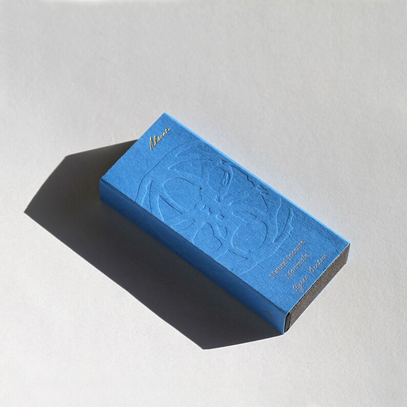 May include: A blue box with a gold embossed design and the text "Numez incense, Hommage, Sugar & Butter".