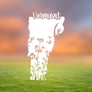 May include: A white silhouette of the state of Vermont with the word "Vermont" above it. The silhouette is filled with a variety of flowers and butterflies. The background is a blurred image of a sunset over a grassy field.