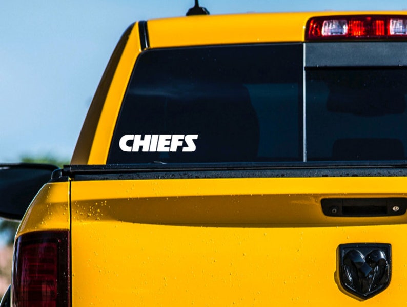 Pode incluir: Uma caminhonete amarela com um adesivo branco "CHIEFS" na janela traseira.