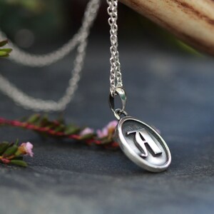 May include: A silver chain necklace with a round pendant featuring the letter "A" in a stylized font.
