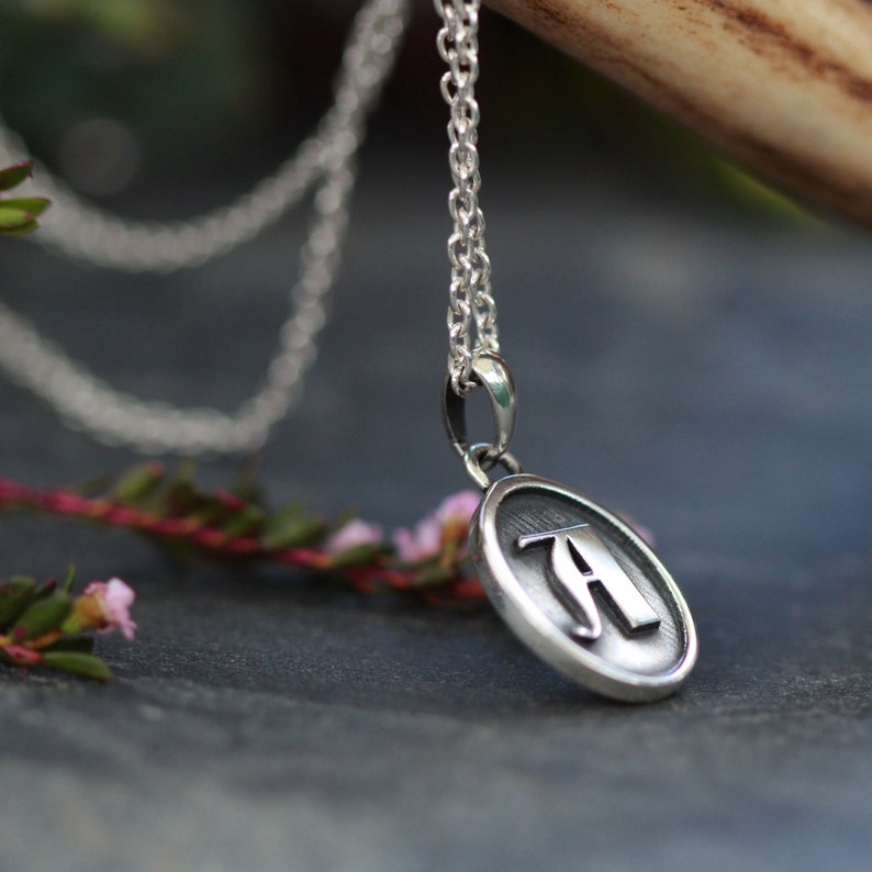 May include: A silver chain necklace with a round pendant featuring the letter "A" in a stylized font.