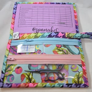 May include: Open sewing organizer with a colorful houndstooth pattern and a light blue interior with a floral design. The organizer has a clear pocket with sewing scissors and a zipper pocket. The text "@jpumakes" is visible.