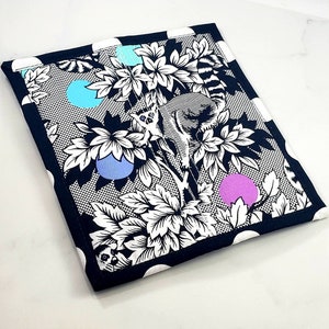 May include: Black and white fabric with a pattern of leaves, a lemur, and polka dots. The polka dots are blue, light blue, and purple.