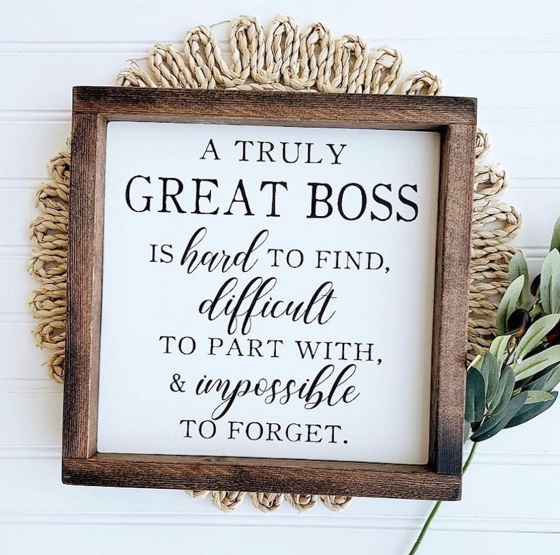 May include: A framed sign with a white background and black text that reads "A truly great boss is hard to find, difficult to part with, & impossible to forget."