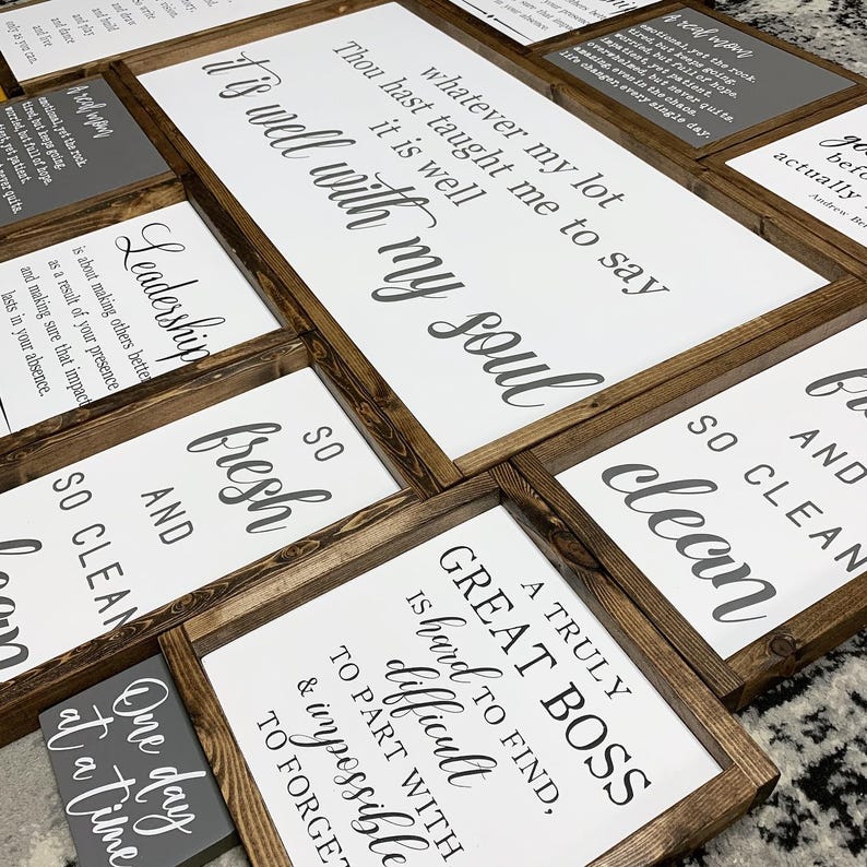 May include: A collection of framed wood signs with inspirational quotes and sayings. The signs are in various sizes and have a rustic farmhouse style. The quotes include "It's well with my soul", "Leadership", "A truly great boss is hard to find", "So clean", and "One day at a time".