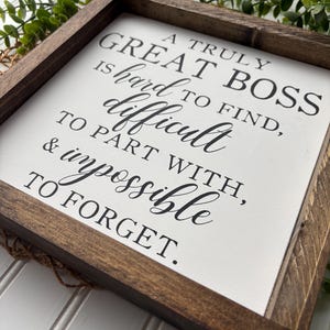 May include: A framed sign with a white background and black text that reads "A truly great boss is hard to find, difficult to part with, & impossible to forget."