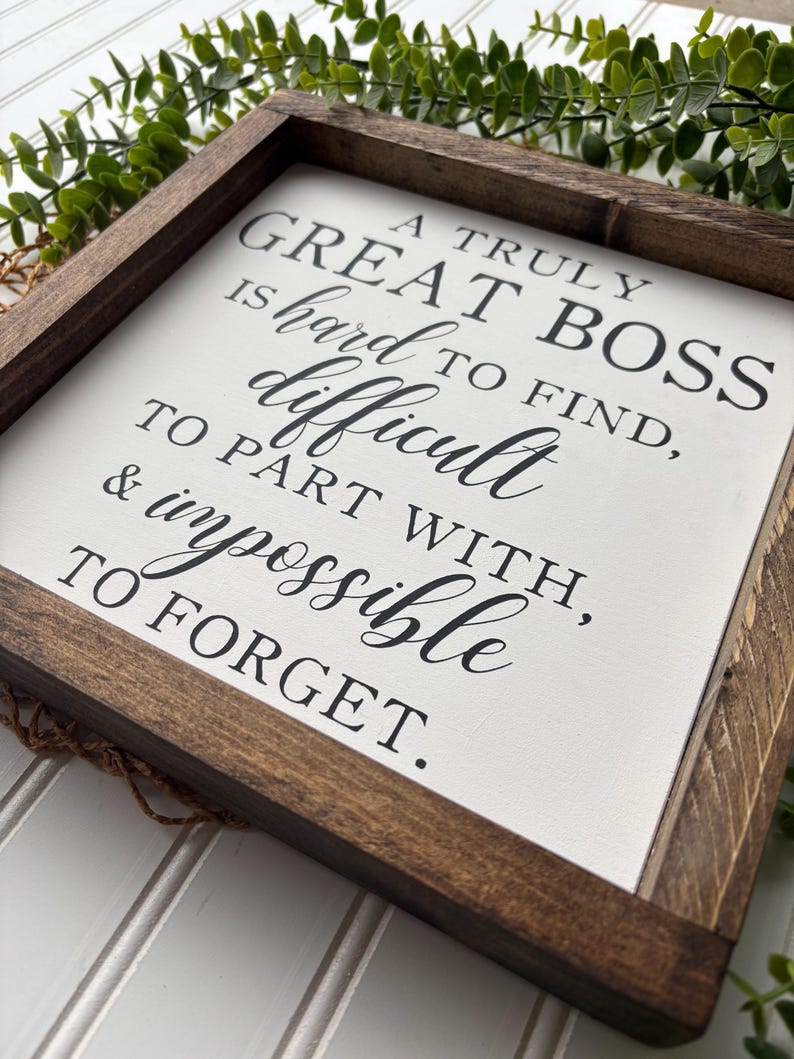 May include: A framed sign with a white background and black text that reads "A truly great boss is hard to find, difficult to part with, & impossible to forget."