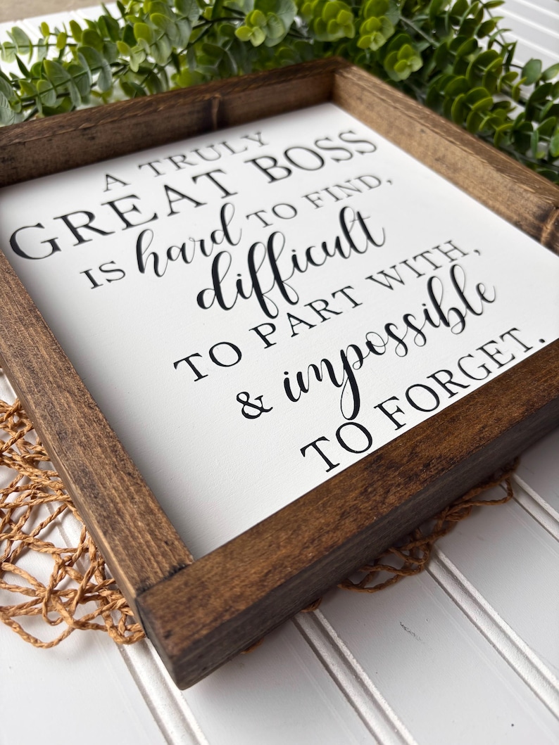 May include: A wooden sign with a white background and black text that reads "A truly great boss is hard to find, difficult to part with, & impossible to forget."