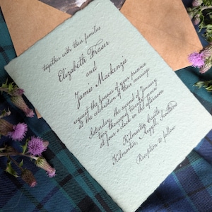 May include: A pale green rectangular wedding invitation with deckled edges and black calligraphy text. The invitation reads: together with their families Elizabeth Fraser and Jamie Mackenzie request the honour of your presence at the celebration of their marriage Saturday, the second of January two thousand twenty-seven at four o'clock in the afternoon Kilmartin Castle, Kilmartin, Argyll, Scotland Reception to follow.