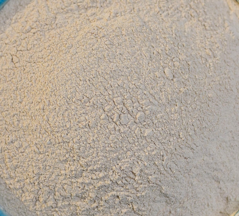 May include: A close-up view of a pile of light beige powder. The powder has a fine, granular texture and is evenly distributed throughout the image.