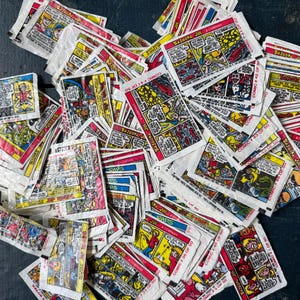 May include: A large collection of Bazooka Joe bubble gum wrappers featuring colorful comic strips. Each rectangular paper wrapper displays various Bazooka Joe and Company comic panels with text, including specific comic numbers like 41 of 50.