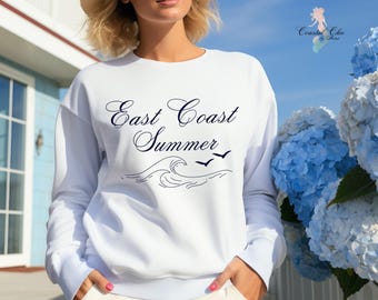 May include: White sweatshirt with the text "East Coast Summer" in a navy blue cursive font. A stylised wave with three birds is below the text.