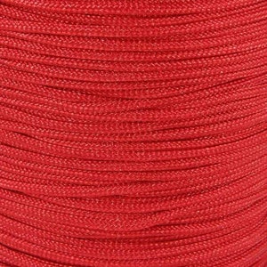 May include: Close-up of a spool of bright red cord. The cord is tightly wound, showing a textured surface with parallel lines. The colour is a vibrant, solid red, suggesting a durable and possibly outdoor-suitable material.