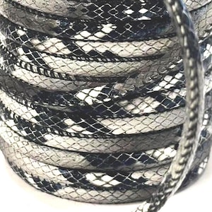 May include: Coiled rope featuring a snakeskin pattern in black, white, and grey. The rope is tightly wound, displaying the detailed scale-like texture. The design resembles a snake's skin, creating a unique visual effect.