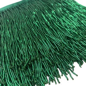 May include: Green beaded fringe trim. The fringe is made of small, cylindrical beads that are strung together to create a long, flowing fringe.