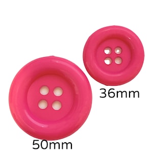 May include: Two pink plastic buttons with four holes each. The larger button is 50mm in diameter and the smaller button is 36mm in diameter.