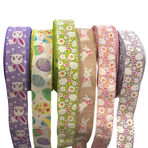 May include: Five rolls of Easter ribbon with different designs. The ribbons feature bunnies, eggs, and flowers in shades of pink, green, purple, and brown.