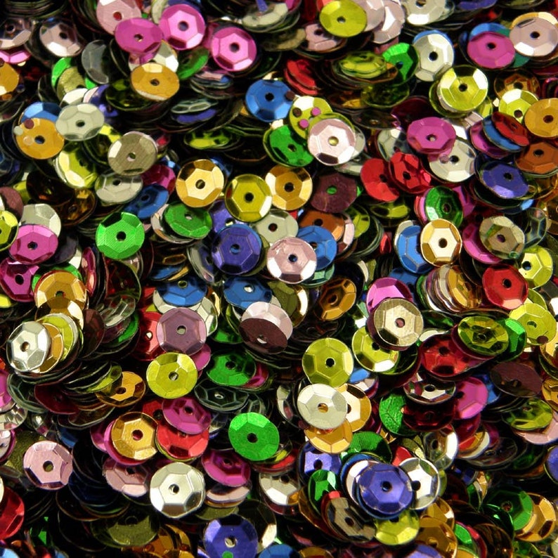 May include: A large assortment of colorful sequins in various shades of green, blue, red, gold, silver, and purple. The sequins are all the same size and shape, and they are arranged in a random pattern.